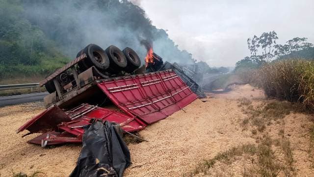 Carreta carregada com soja pega fogo após tombar na BR-324